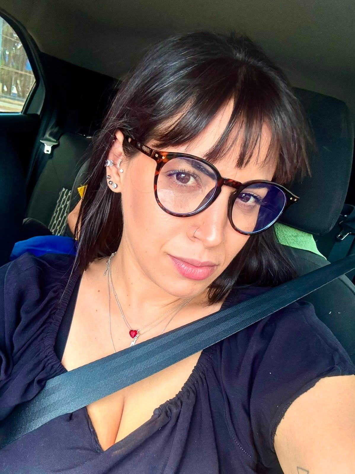 Retrato de Taís Alves, usando óculos, dentro de um carro.